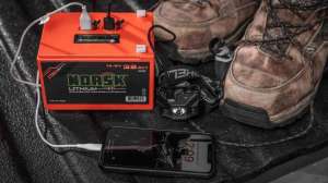 Cropped Norsk Lithuim 32 Ah Battery with build in USB ports charging a phone and a headlamp while Truck Camping durring hunting season